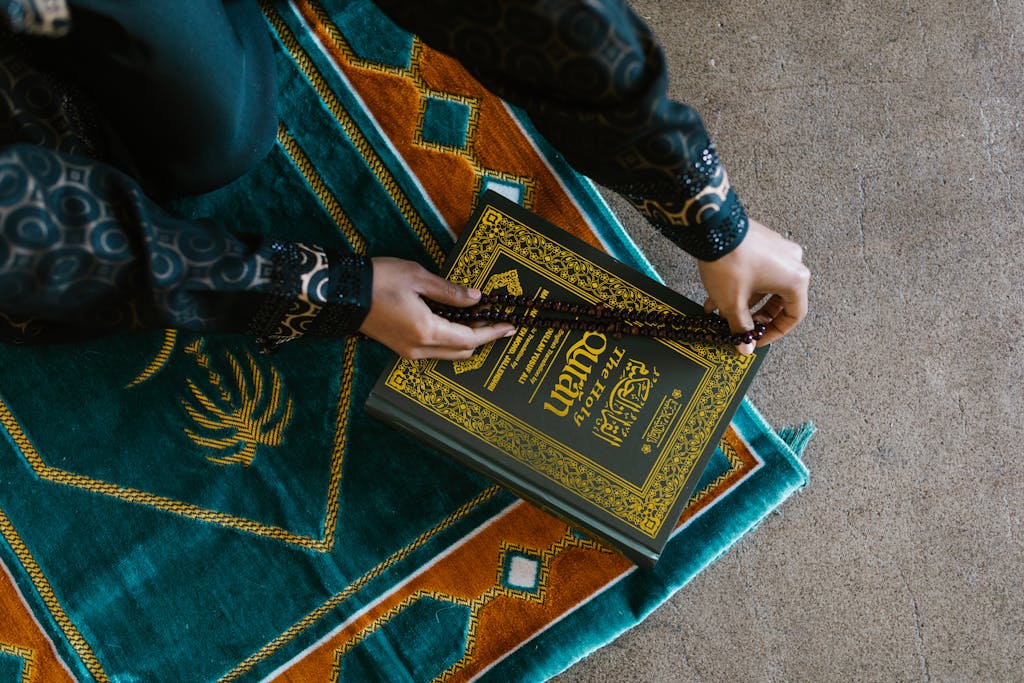 Hands of a Person Holding a Prayer Beads on a Book